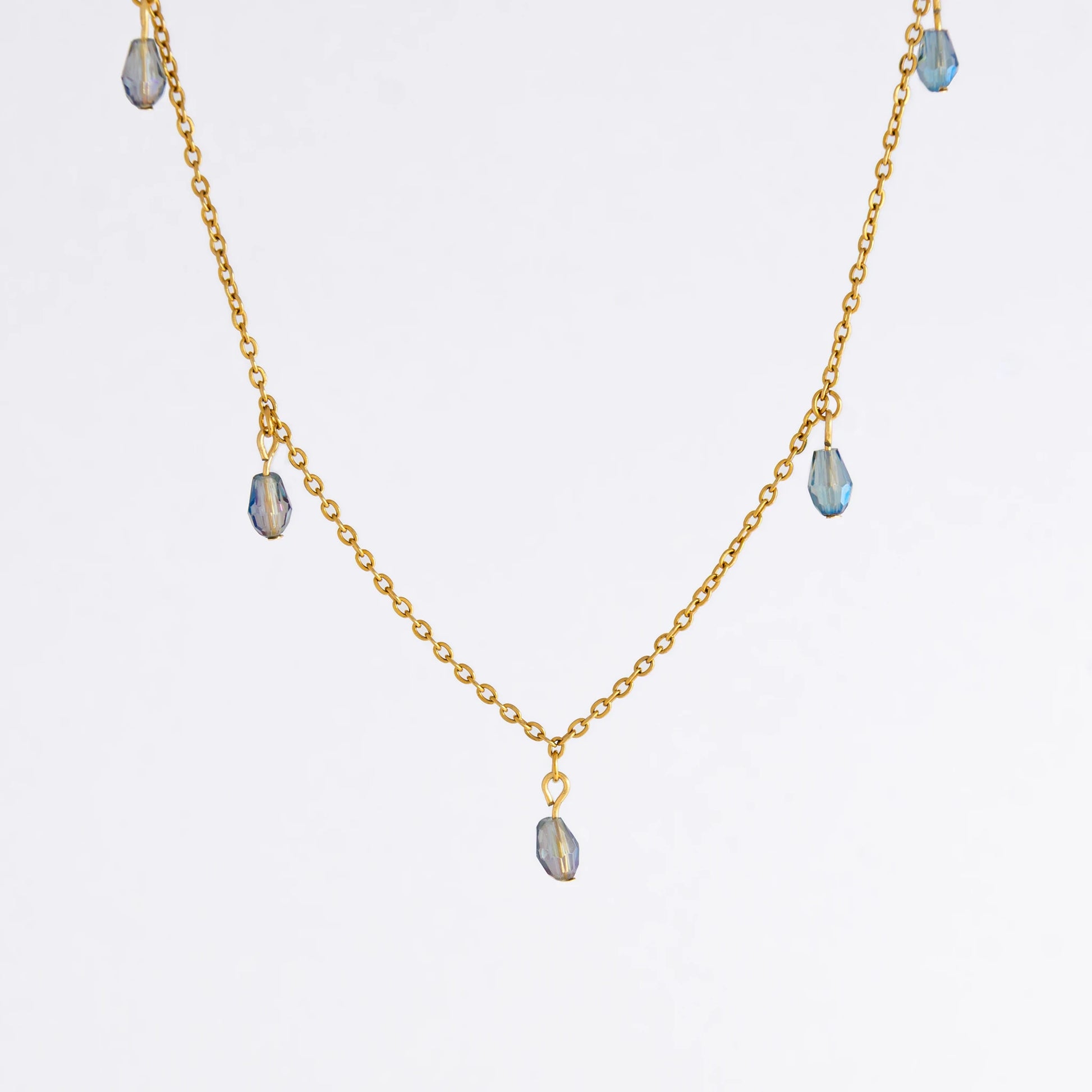 Gold satellite necklace with small purple glass beads on a light gray background