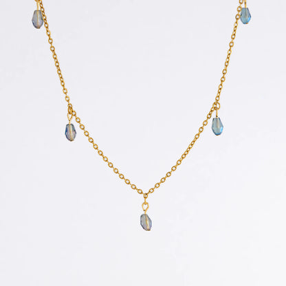 Gold satellite necklace with small purple glass beads on a light gray background