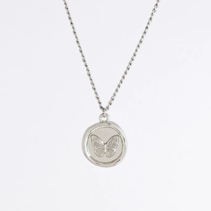 Silver curb necklace with a round butterfly pendant on a light gray background