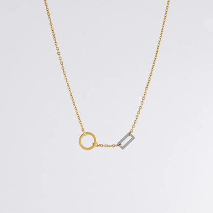 A gold chain necklace with a geometric design featuring a circle of brushed gold and a polished silver bar charm.