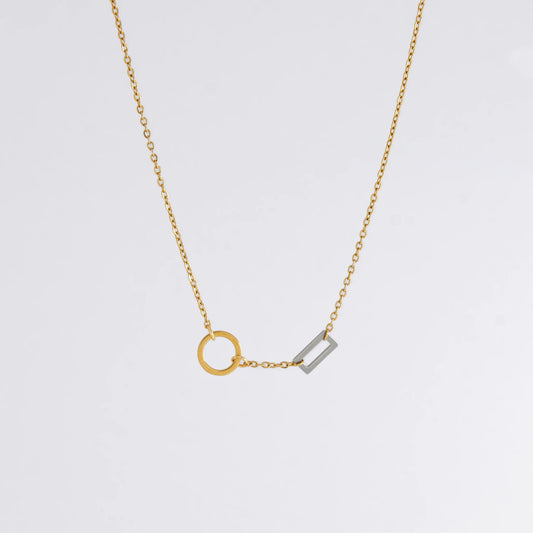 A gold chain necklace with a geometric design featuring a circle of brushed gold and a polished silver bar charm.