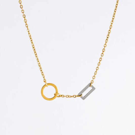 A gold chain necklace with a geometric design featuring a circle of brushed gold and a polished silver bar charm.