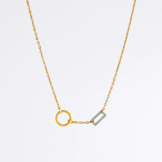 A gold chain necklace with a geometric design featuring a circle of brushed gold and a polished silver bar charm.