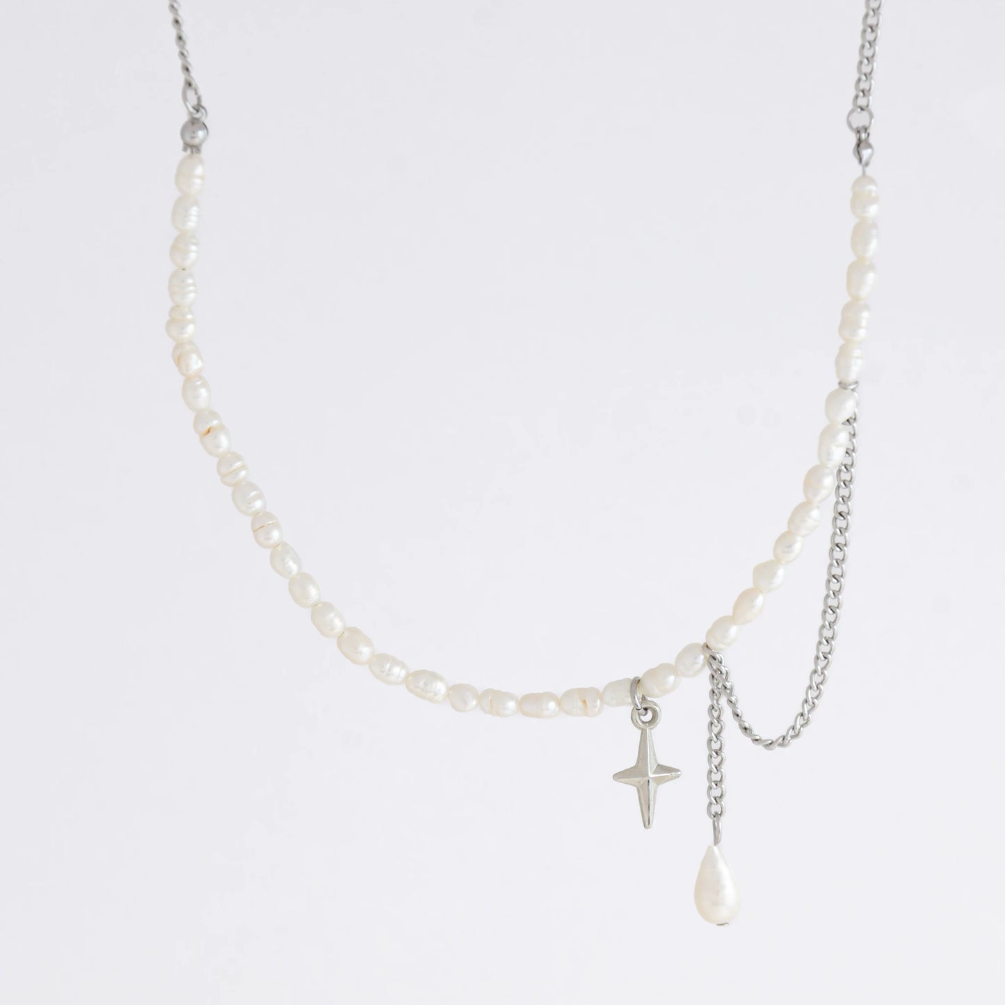 Pearl choker necklace with a small star pendant and a layering chain with pearl on a light gray background