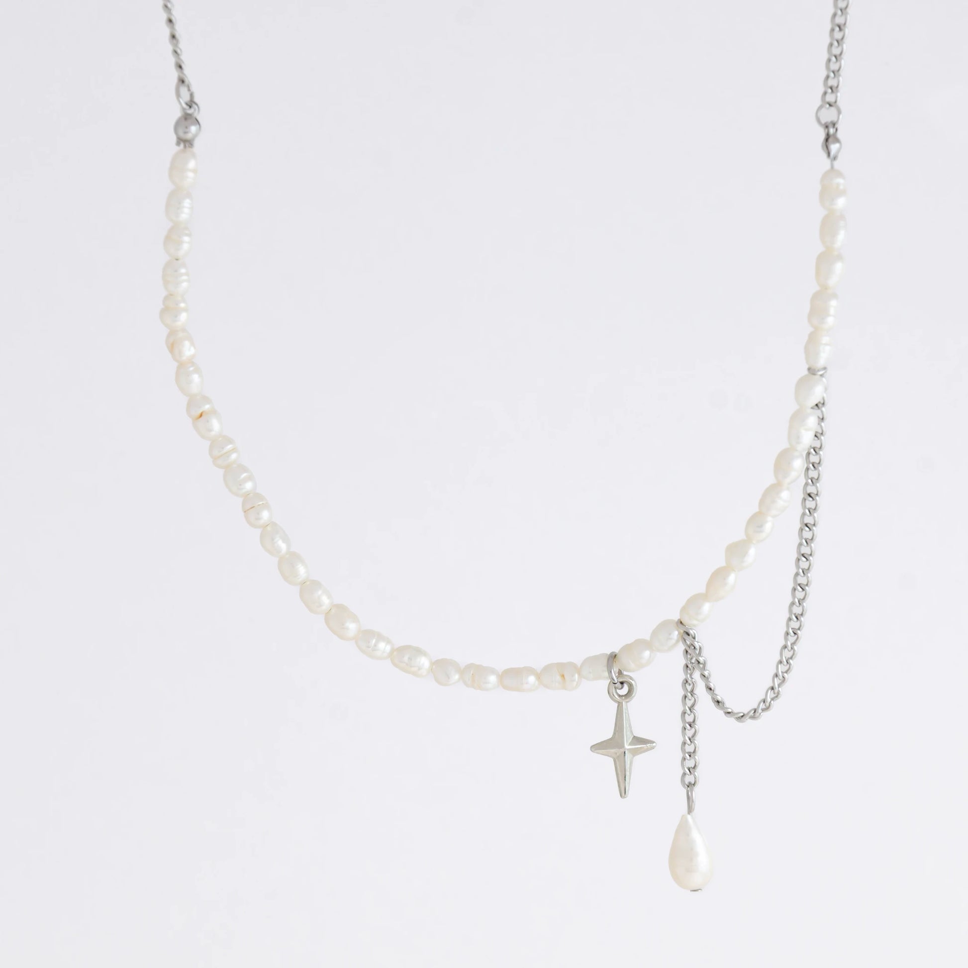 Pearl choker necklace with a small star pendant and a layering chain with pearl on a light gray background