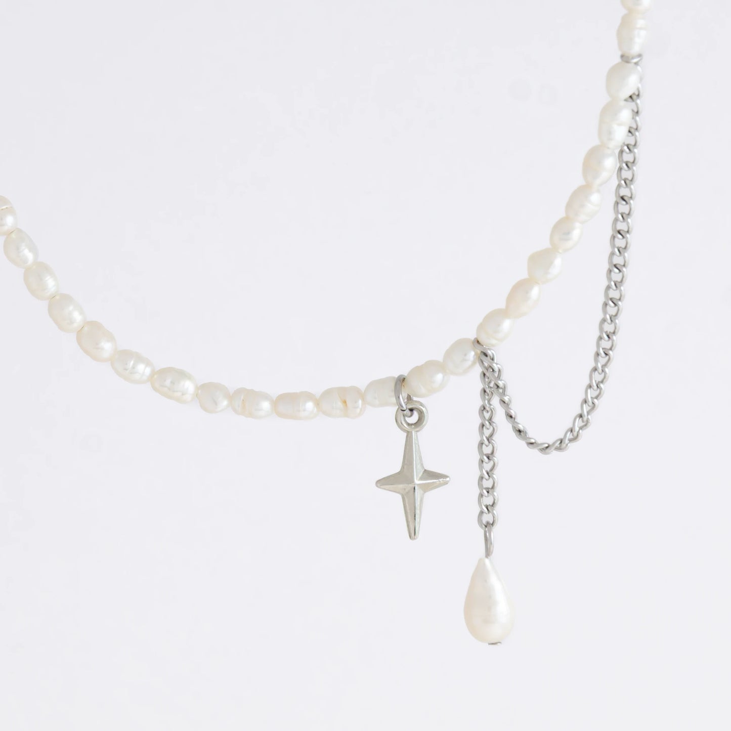 Pearl choker necklace with a small star pendant and a layering chain with pearl on a light gray background