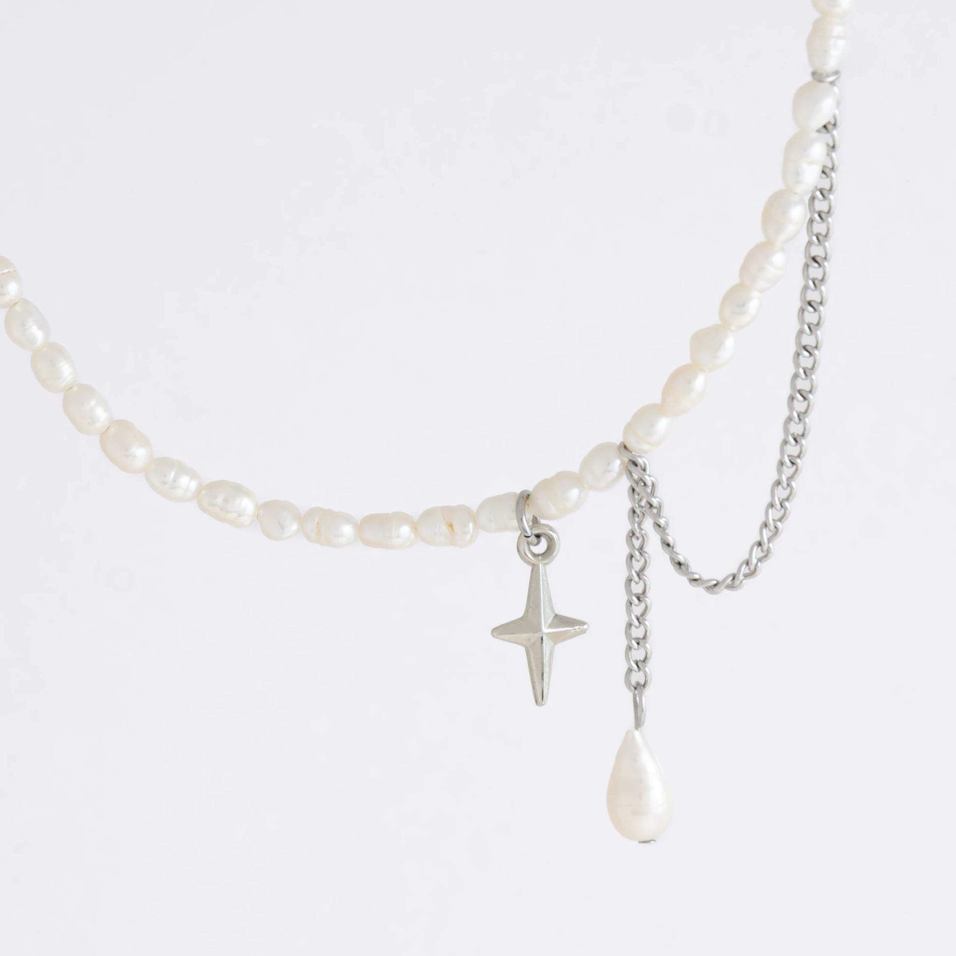 Pearl choker necklace with a small star pendant and a layering chain with pearl on a light gray background