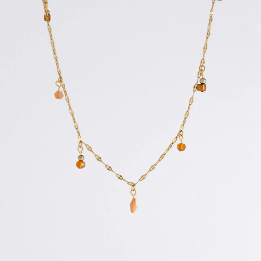 Delicate gold satellite necklace with small orange beads on a light gray background