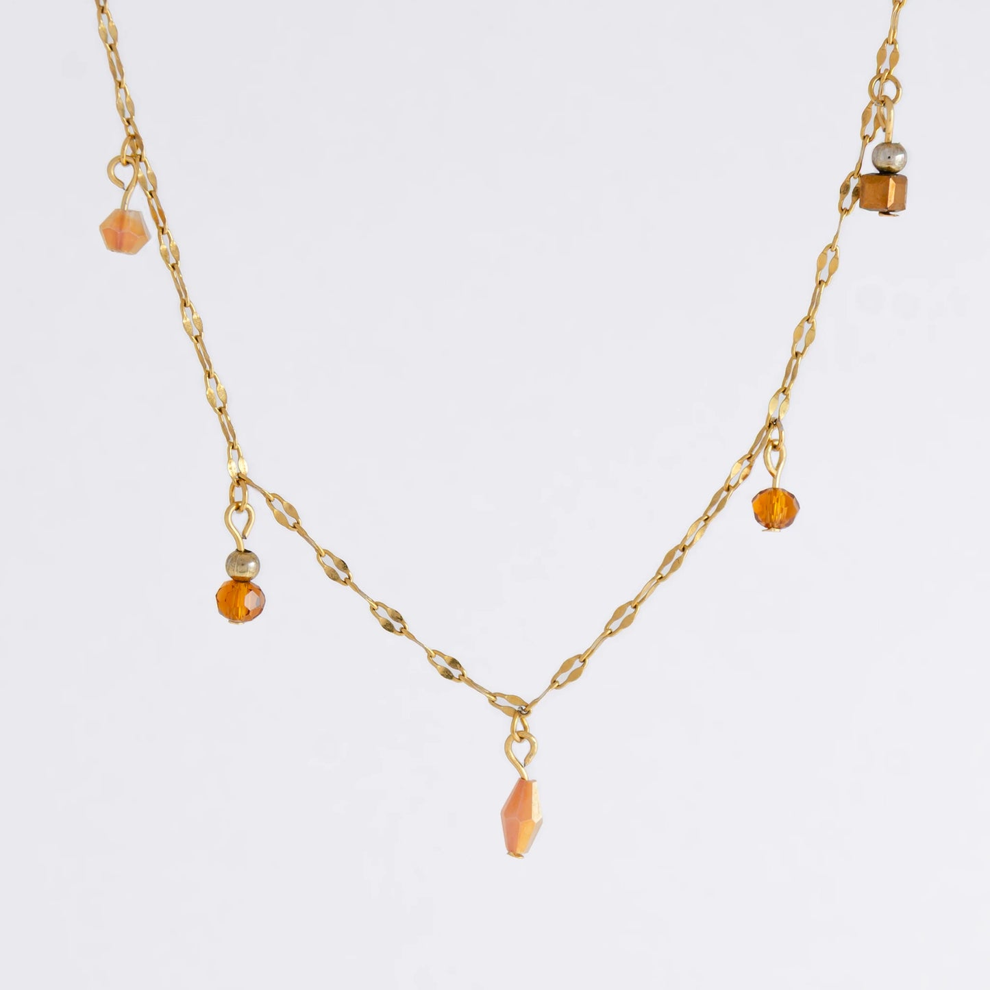 Delicate gold satellite necklace with small orange beads on a light gray background