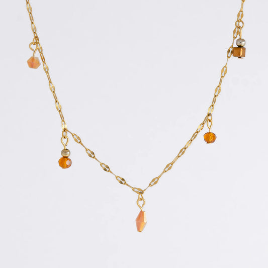 Delicate gold satellite necklace with small orange beads on a light gray background