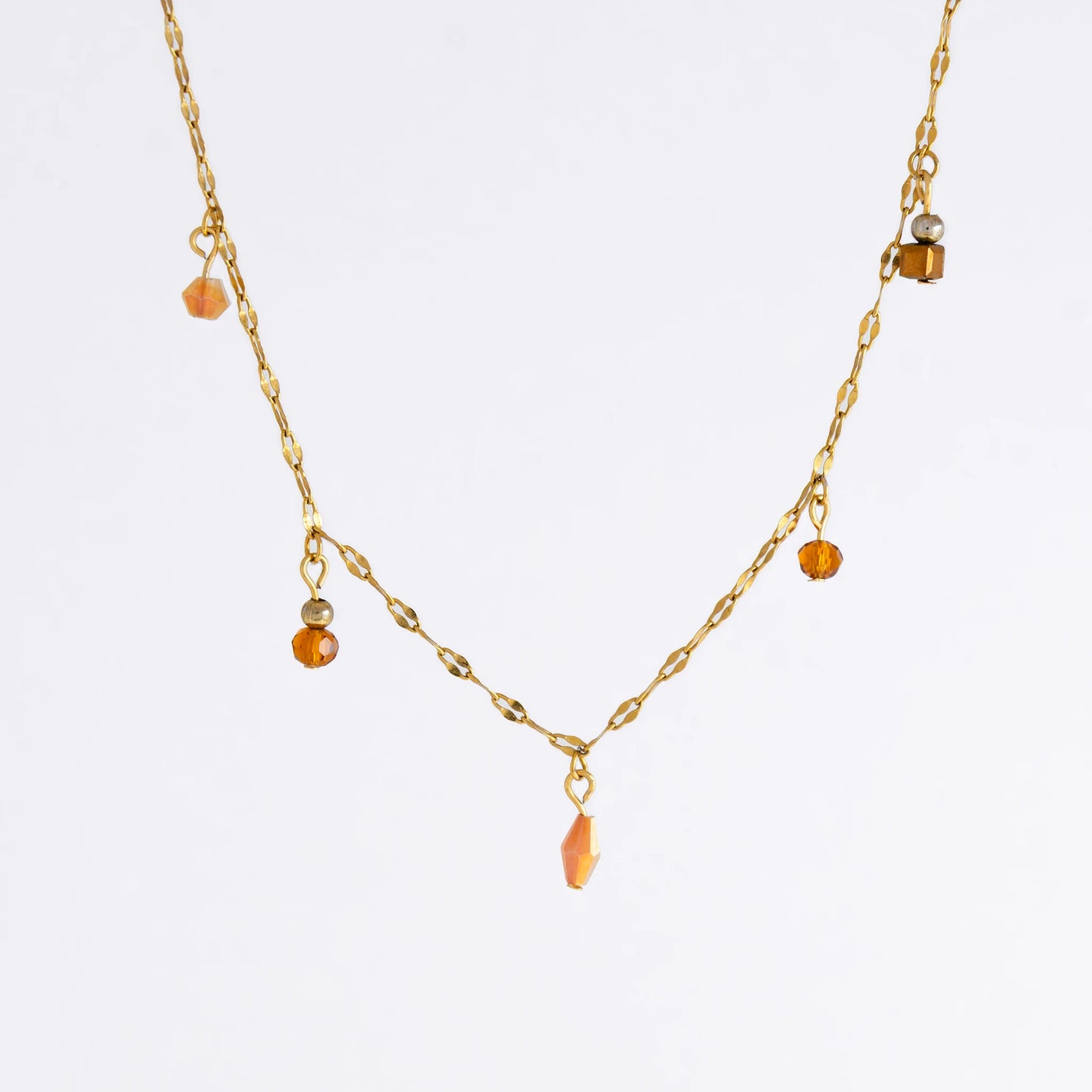 Delicate gold satellite necklace with small orange beads on a light gray background