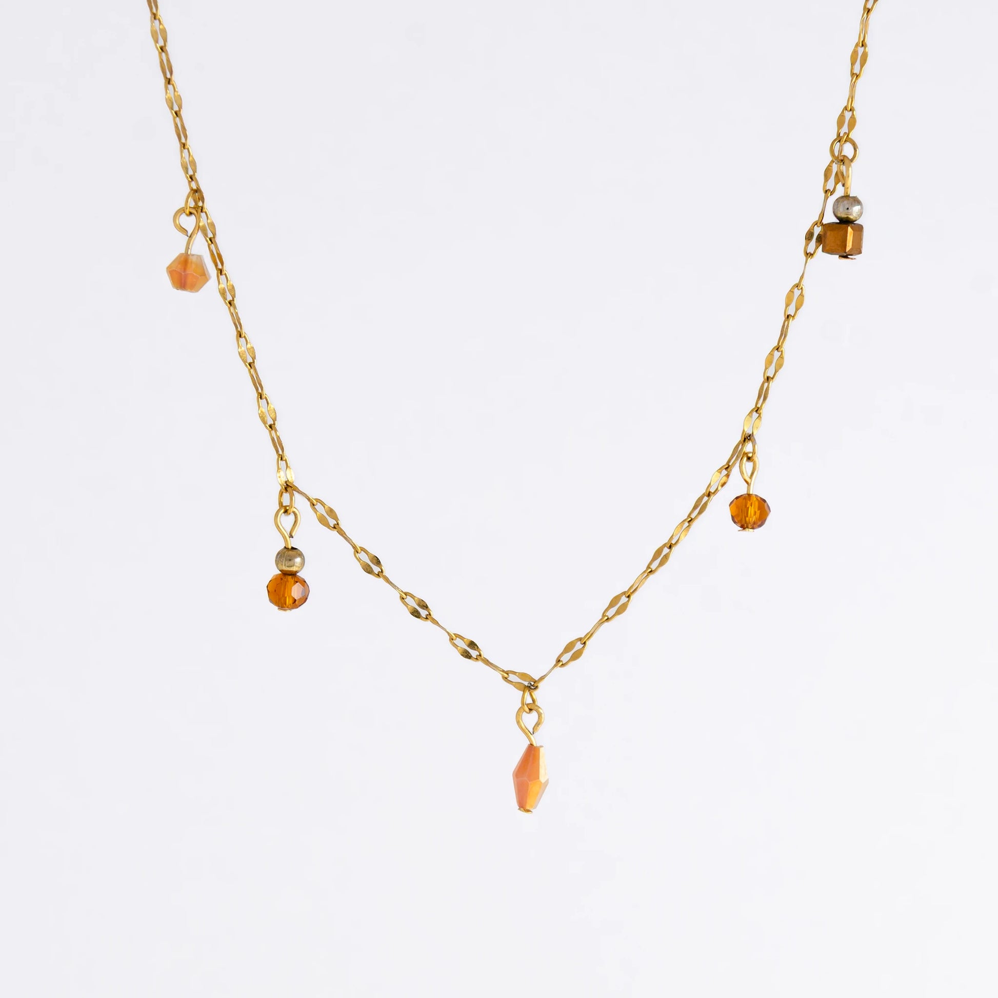 Delicate gold satellite necklace with small orange beads on a light gray background