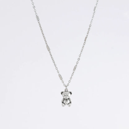 Dainty silver bar link chain with a teddy bear charm for minimalistic fashion or for layering jewelry on a light gray background