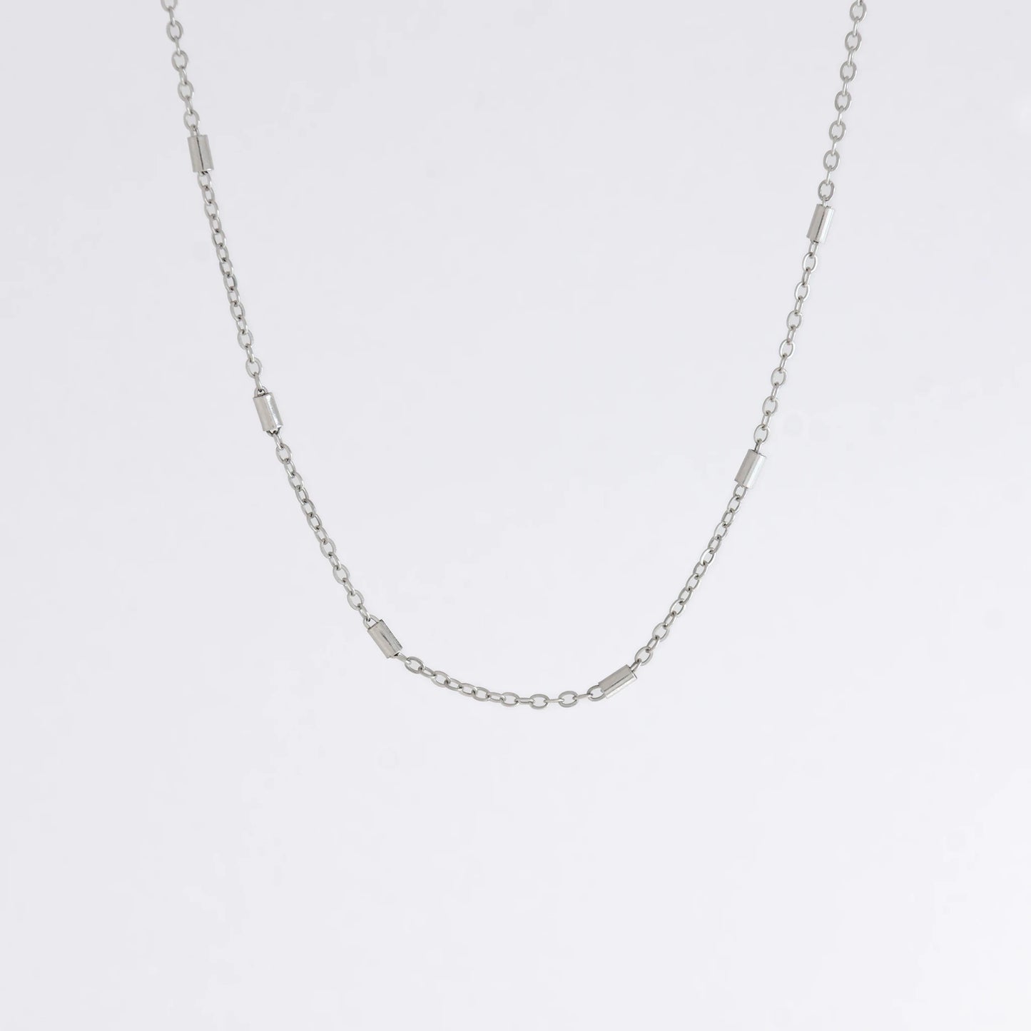 Dainty silver bar link chain for minimalistic fashion or for layering jewelry on a light gray background