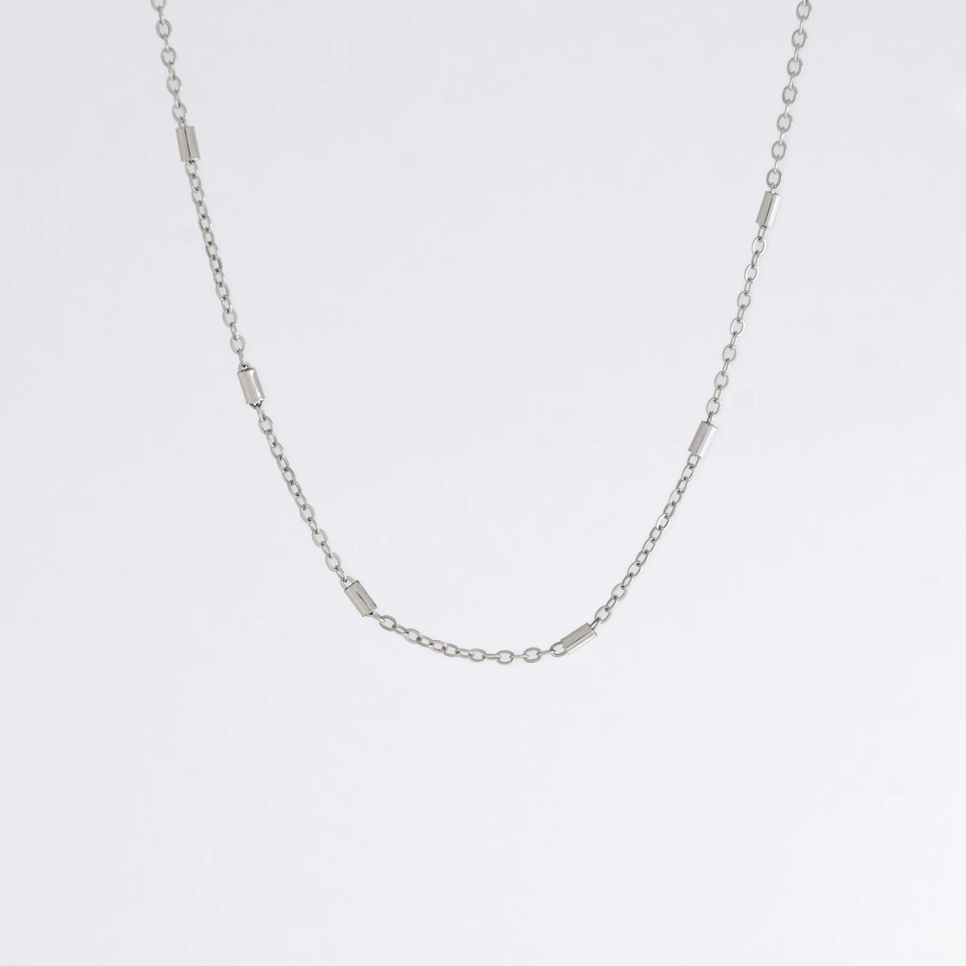 Dainty silver bar link chain for minimalistic fashion or for layering jewelry on a light gray background