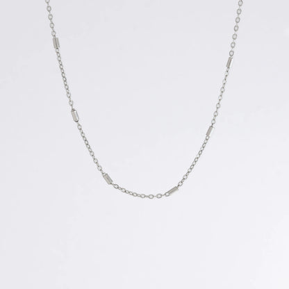 Dainty silver bar link chain for minimalistic fashion or for layering jewelry on a light gray background