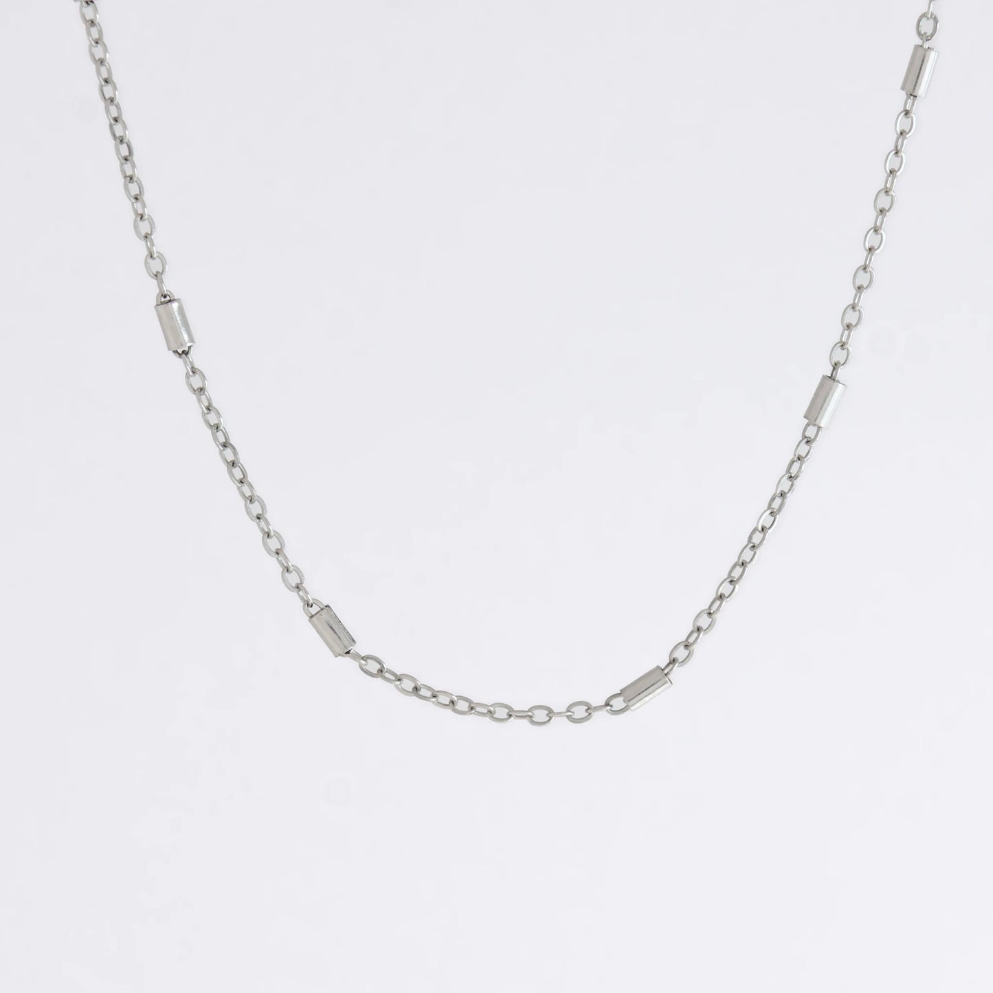 Dainty silver bar link chain for minimalistic fashion or for layering jewelry on a light gray background