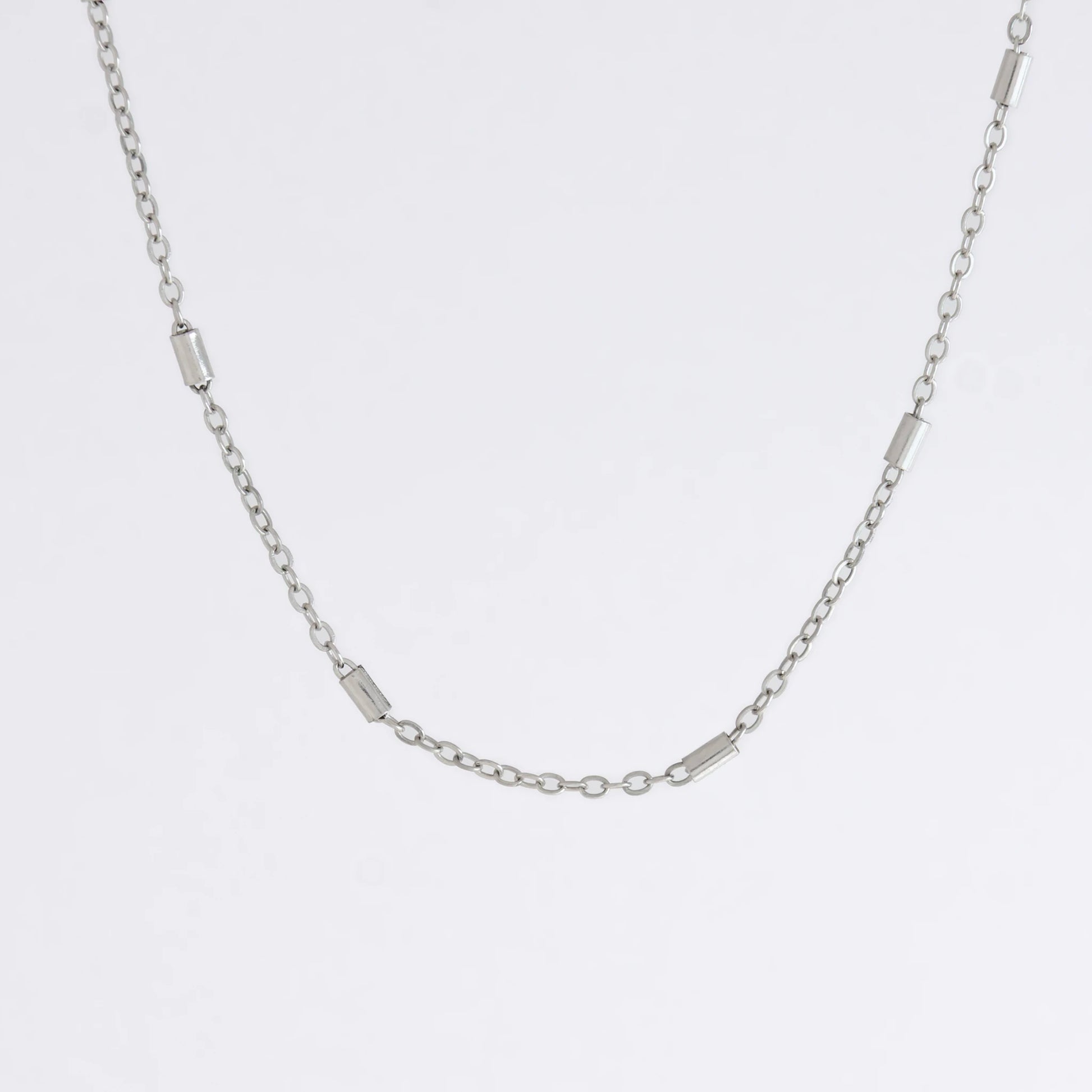 Dainty silver bar link chain for minimalistic fashion or for layering jewelry on a light gray background
