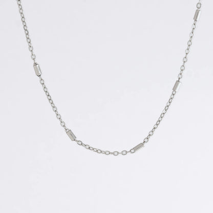 Dainty silver bar link chain for minimalistic fashion or for layering jewelry on a light gray background