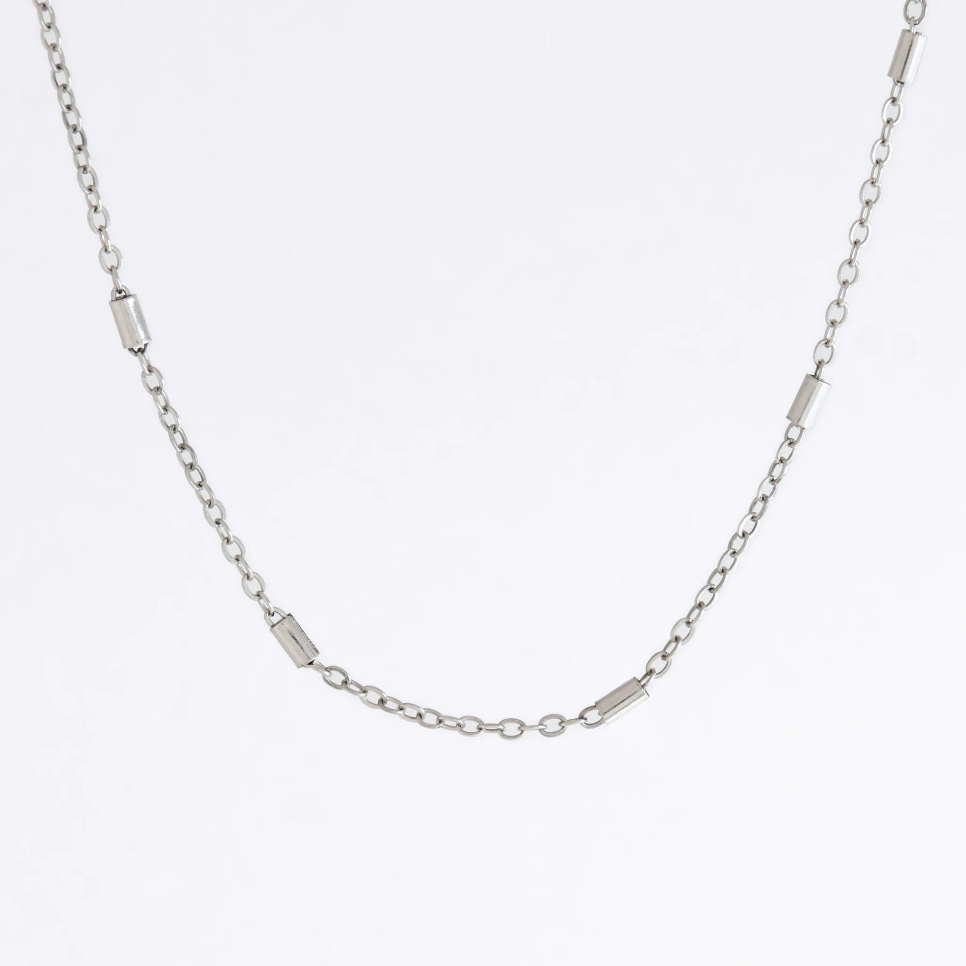 Dainty silver bar link chain for minimalistic fashion or for layering jewelry on a light gray background