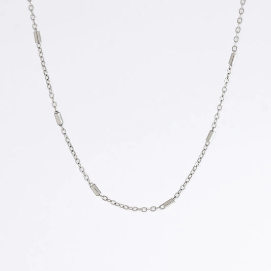 Dainty silver bar link chain for minimalistic fashion or for layering jewelry on a light gray background