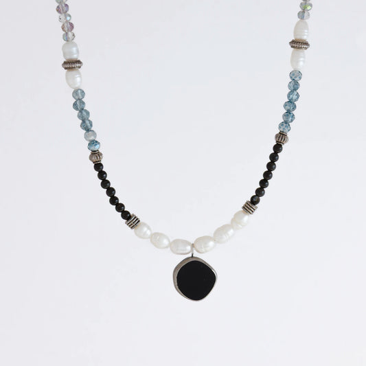 Silver beaded necklace with black pendant and multicolored beads on a light gray background