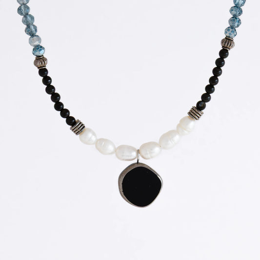 Silver beaded necklace with black pendant and multicolored beads on a light gray background