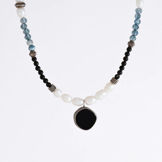 Silver beaded necklace with black pendant and multicolored beads on a light gray background