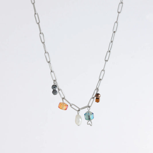 Silver paperclip chain necklace with small bead charms including freshwater pearls, black, blue, and orange glass beads on a light gray background