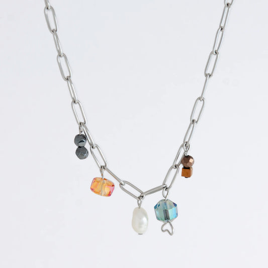 Silver paperclip chain necklace with small bead charms including freshwater pearls, black, blue, and orange glass beads on a light gray background