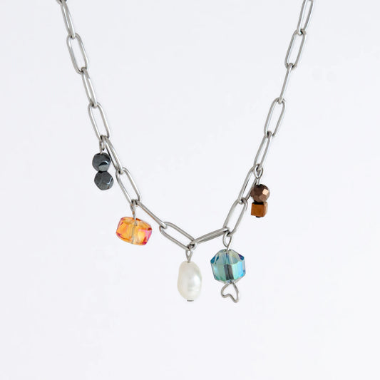 Silver paperclip chain necklace with small bead charms including freshwater pearls, black, blue, and orange glass beads on a light gray background