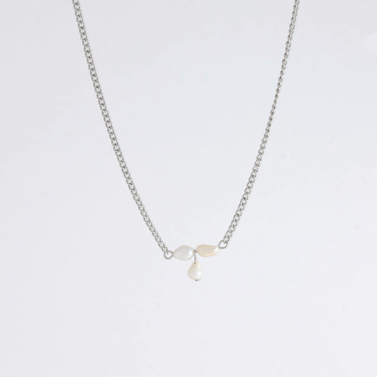 Silver necklace non-tarnish with three pearl beads on a light gray background