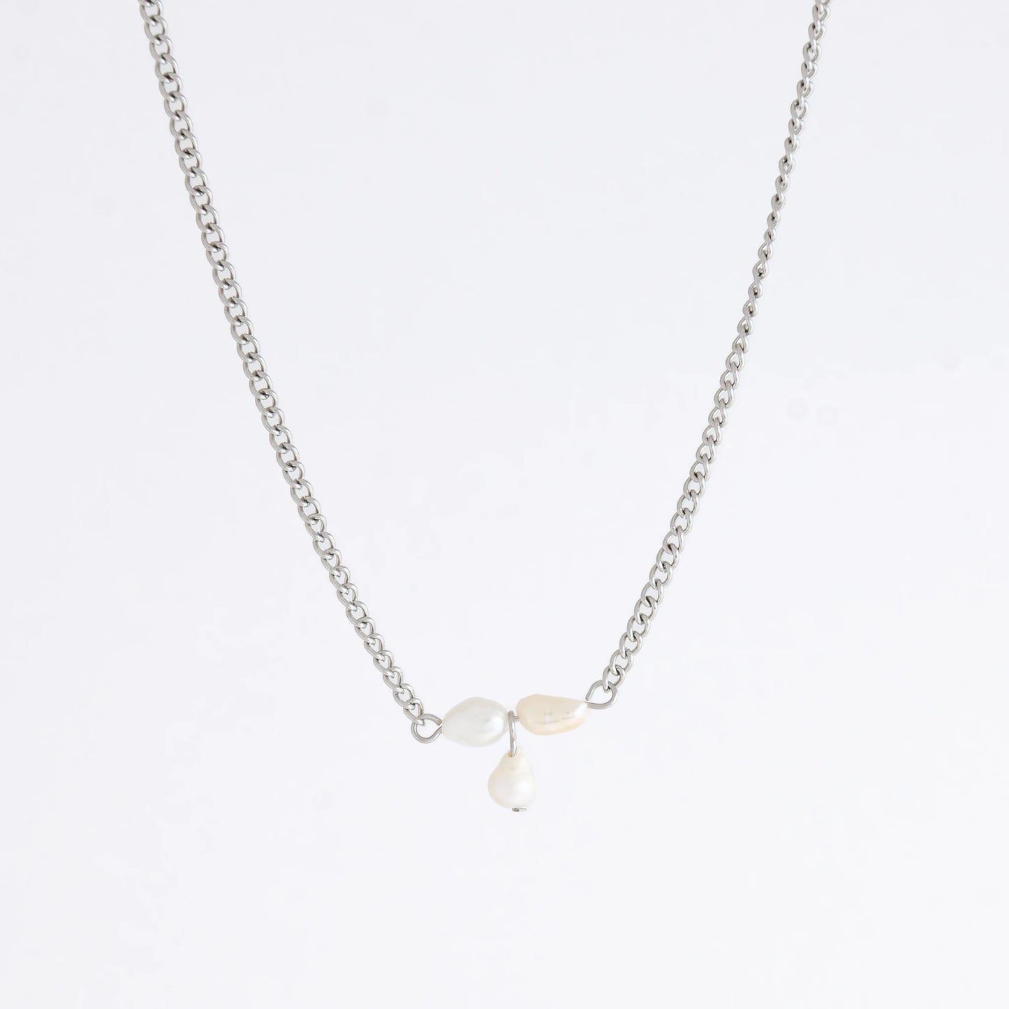 Silver necklace non-tarnish with three pearl beads on a light gray background