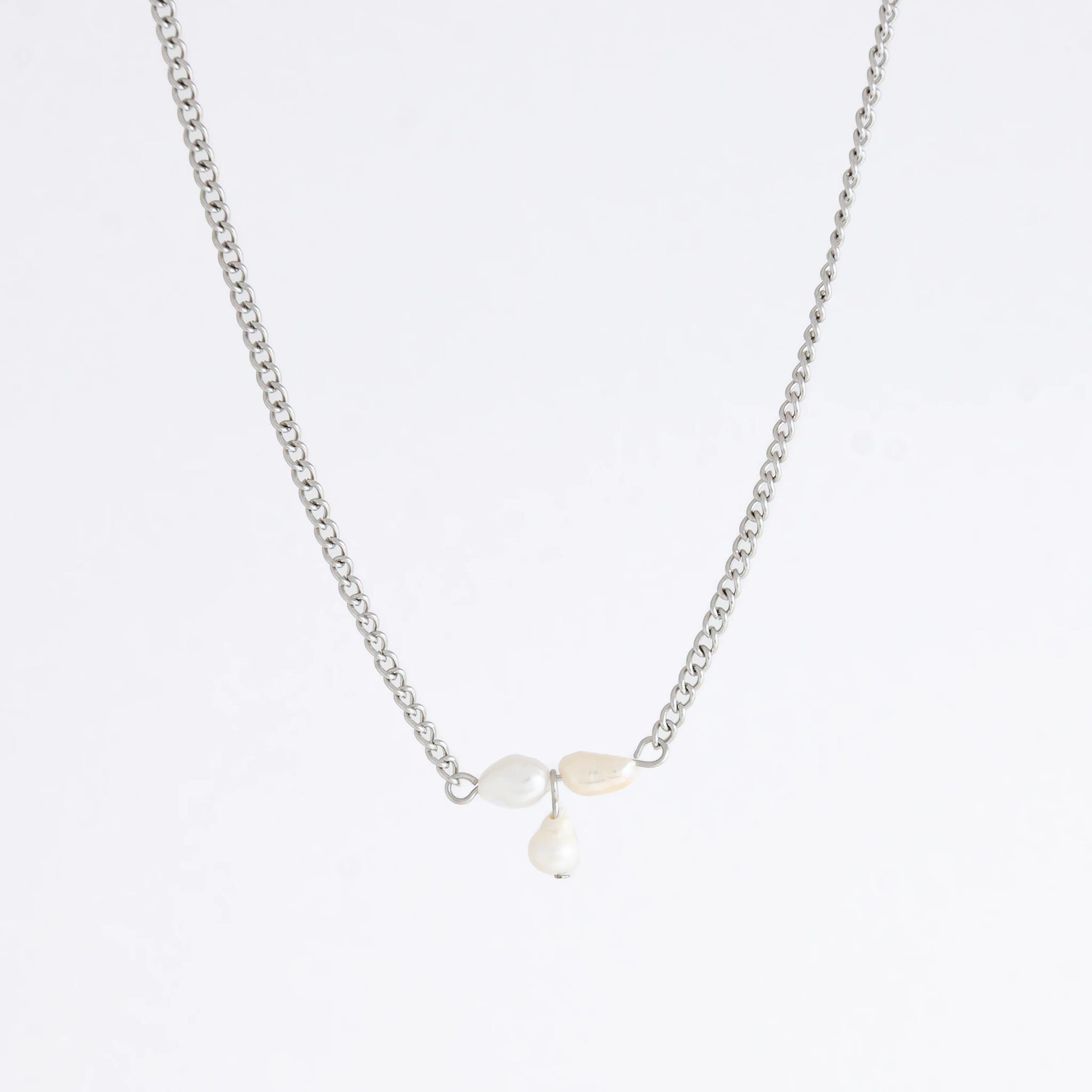 Silver necklace non-tarnish with three pearl beads on a light gray background
