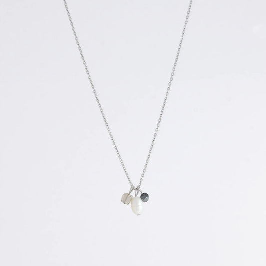 Silver dainty necklace with three small charms made of glass beads and pearls on a white background