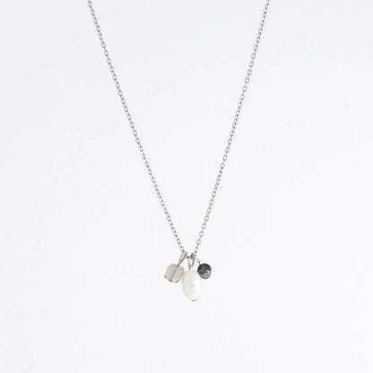 Silver dainty necklace with three small charms made of glass beads and pearls on a white background