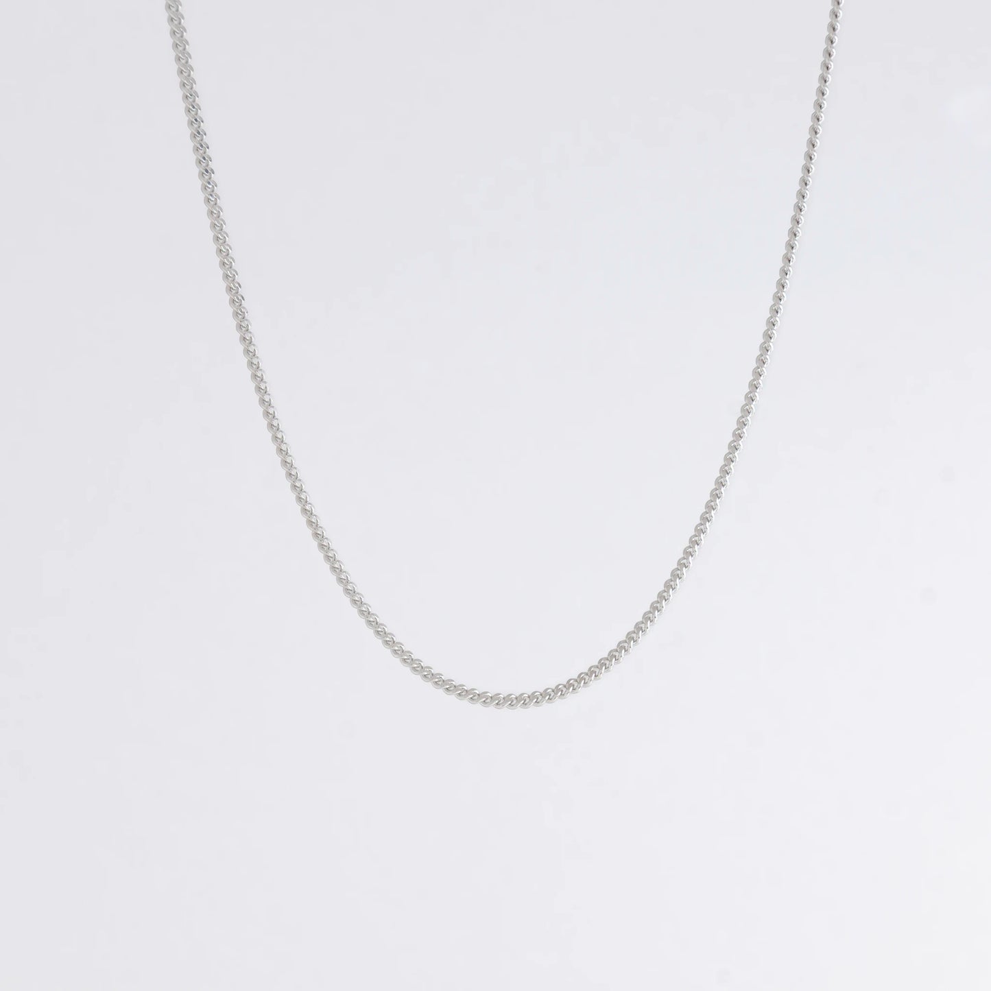 Dainty silver curb chain for minimalistic fashion or for layering jewelry on a light gray background