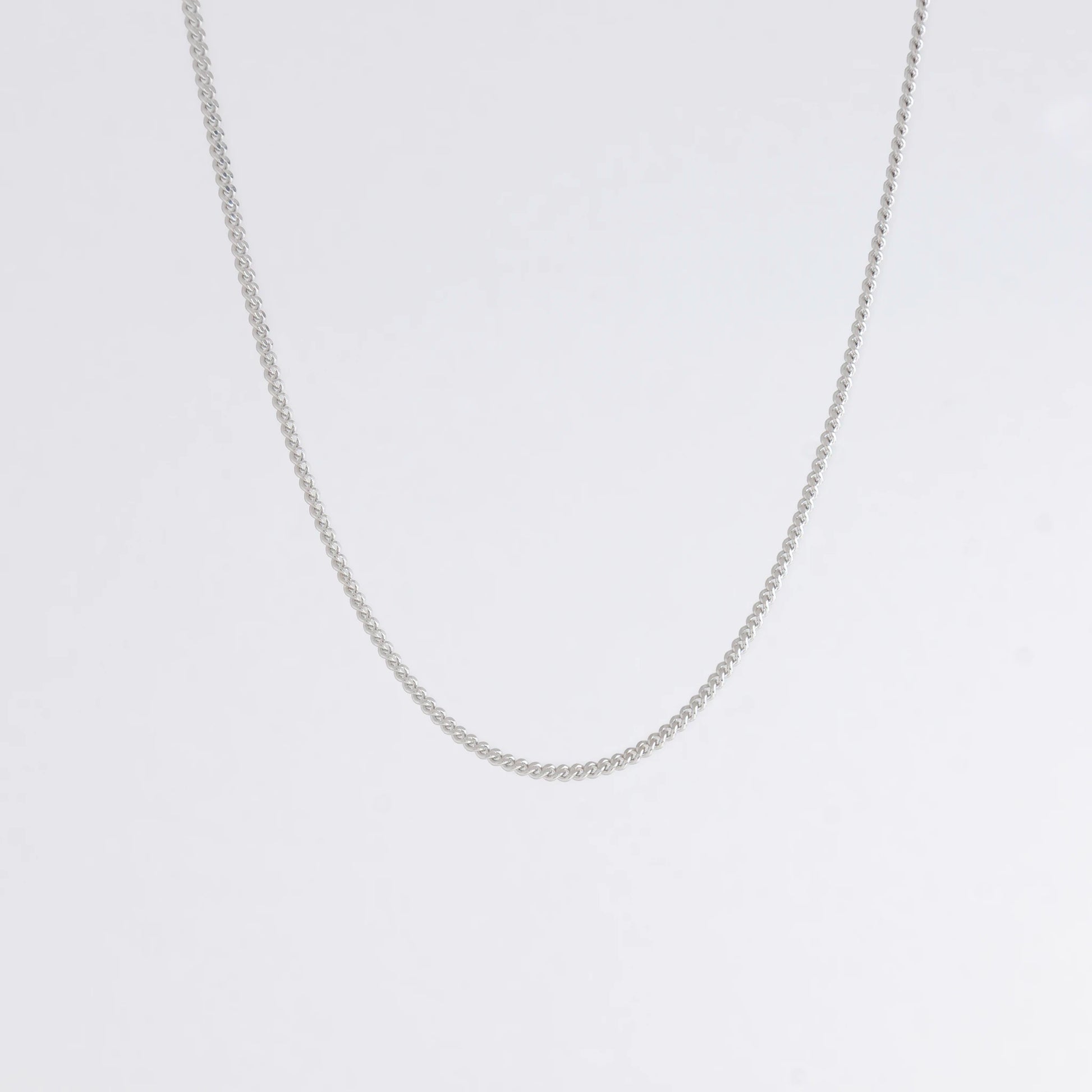 Dainty silver curb chain for minimalistic fashion or for layering jewelry on a light gray background