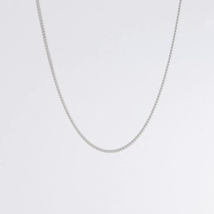 Dainty silver curb chain for minimalistic fashion or for layering jewelry on a light gray background