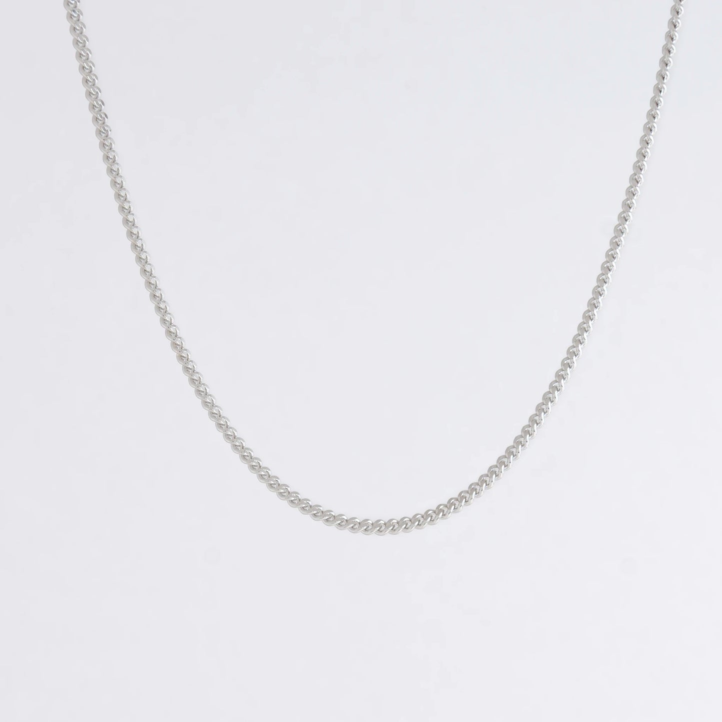 Dainty silver curb chain for minimalistic fashion or for layering jewelry on a light gray background