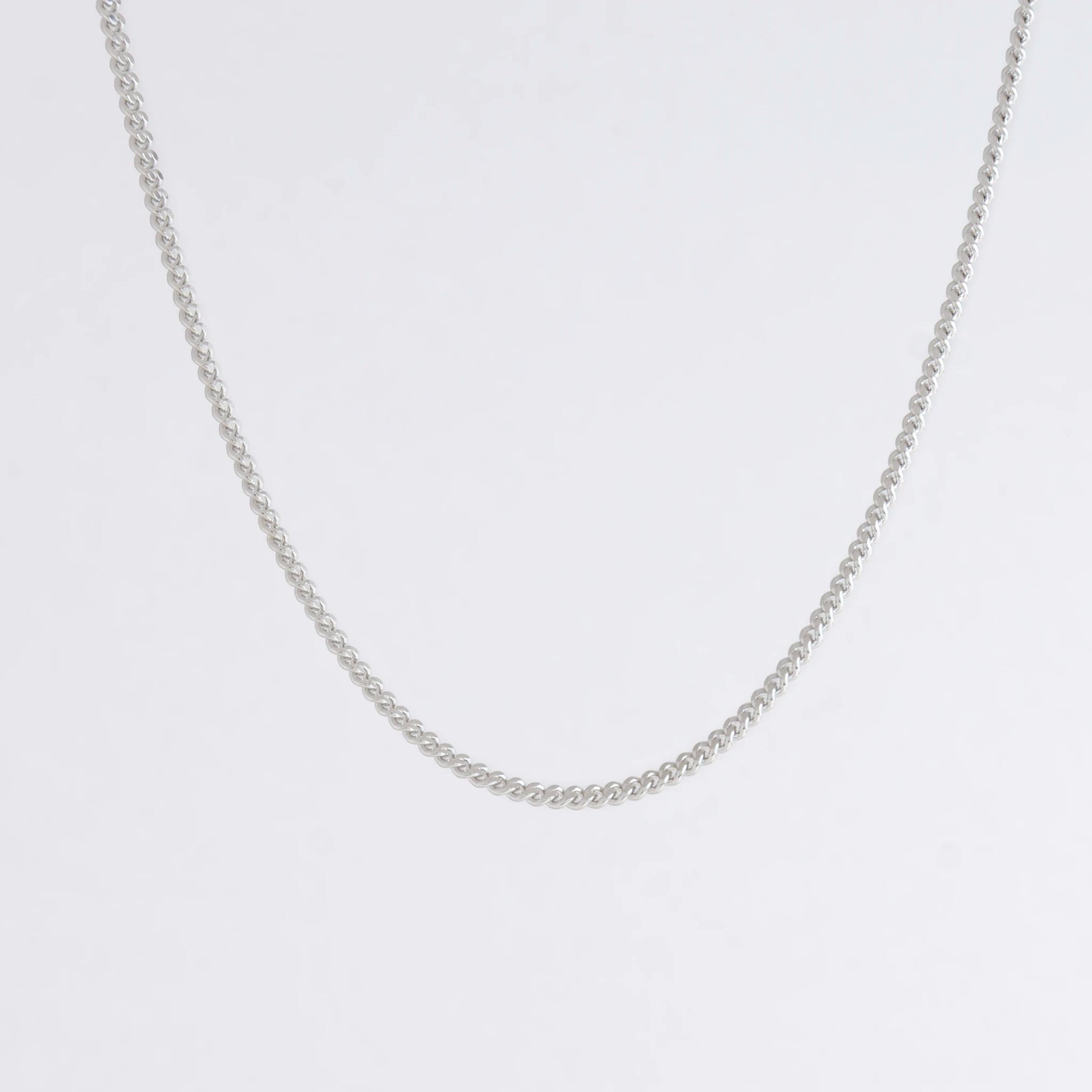 Dainty silver curb chain for minimalistic fashion or for layering jewelry on a light gray background