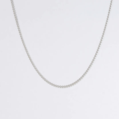 Dainty silver curb chain for minimalistic fashion or for layering jewelry on a light gray background