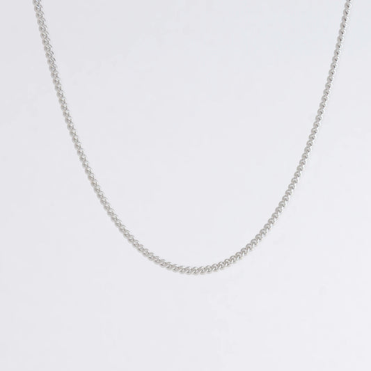 Dainty silver curb chain for minimalistic fashion or for layering jewelry on a light gray background