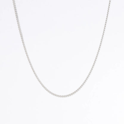 Dainty silver curb chain for minimalistic fashion or for layering jewelry on a light gray background
