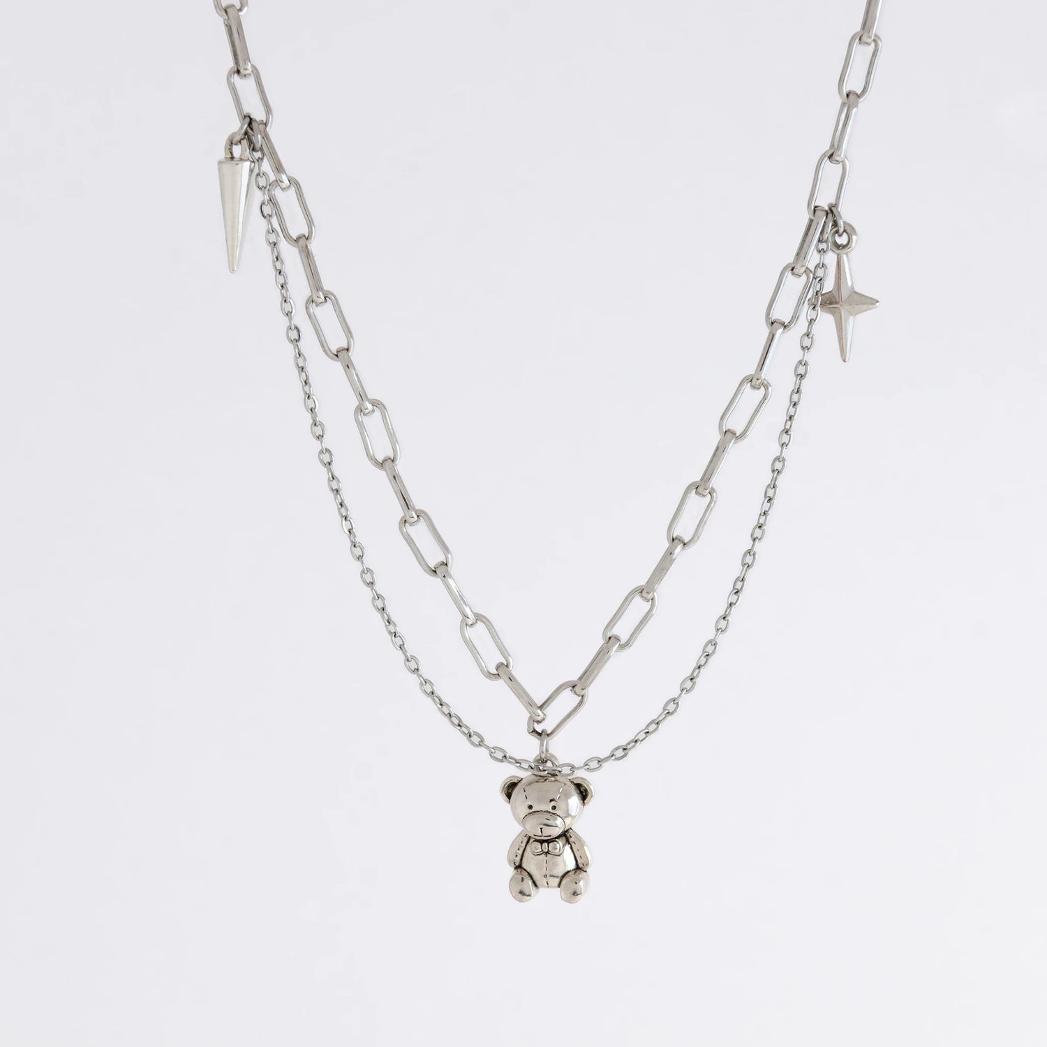 Silver chain necklace with a teddy bear pendant on a white background