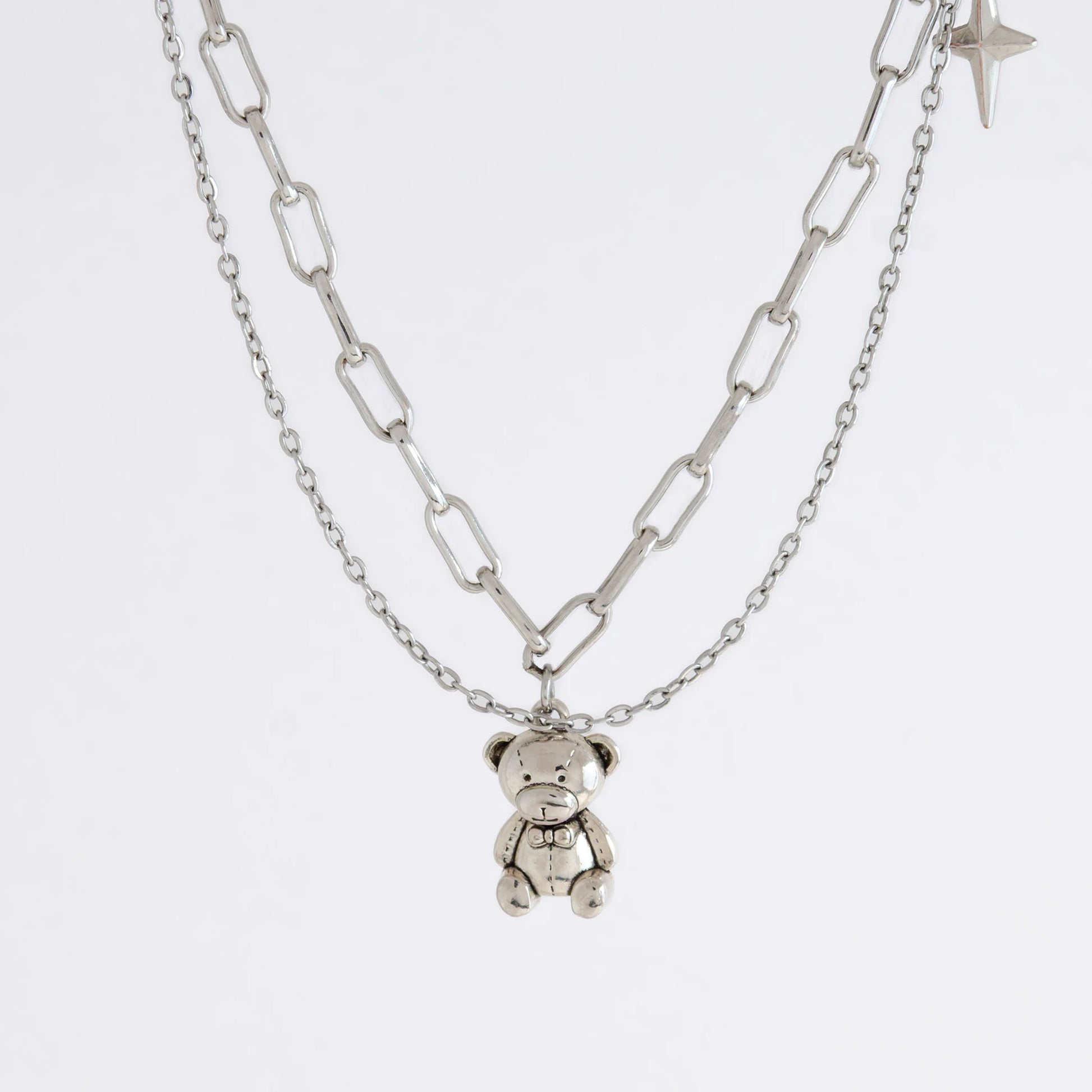 Silver chain necklace with a teddy bear charm on a white background