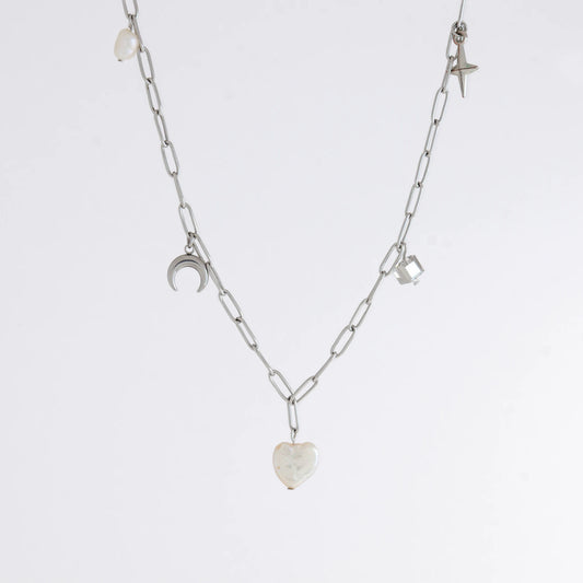 Silver chain charm necklace with pearl pendants, glass bead, and star pendants on a light gray background