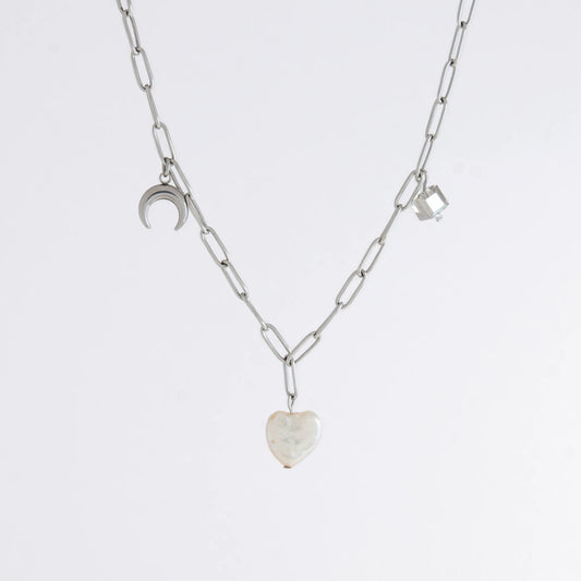 Silver chain charm necklace with pearl pendants, glass bead, and star pendants on a light gray background