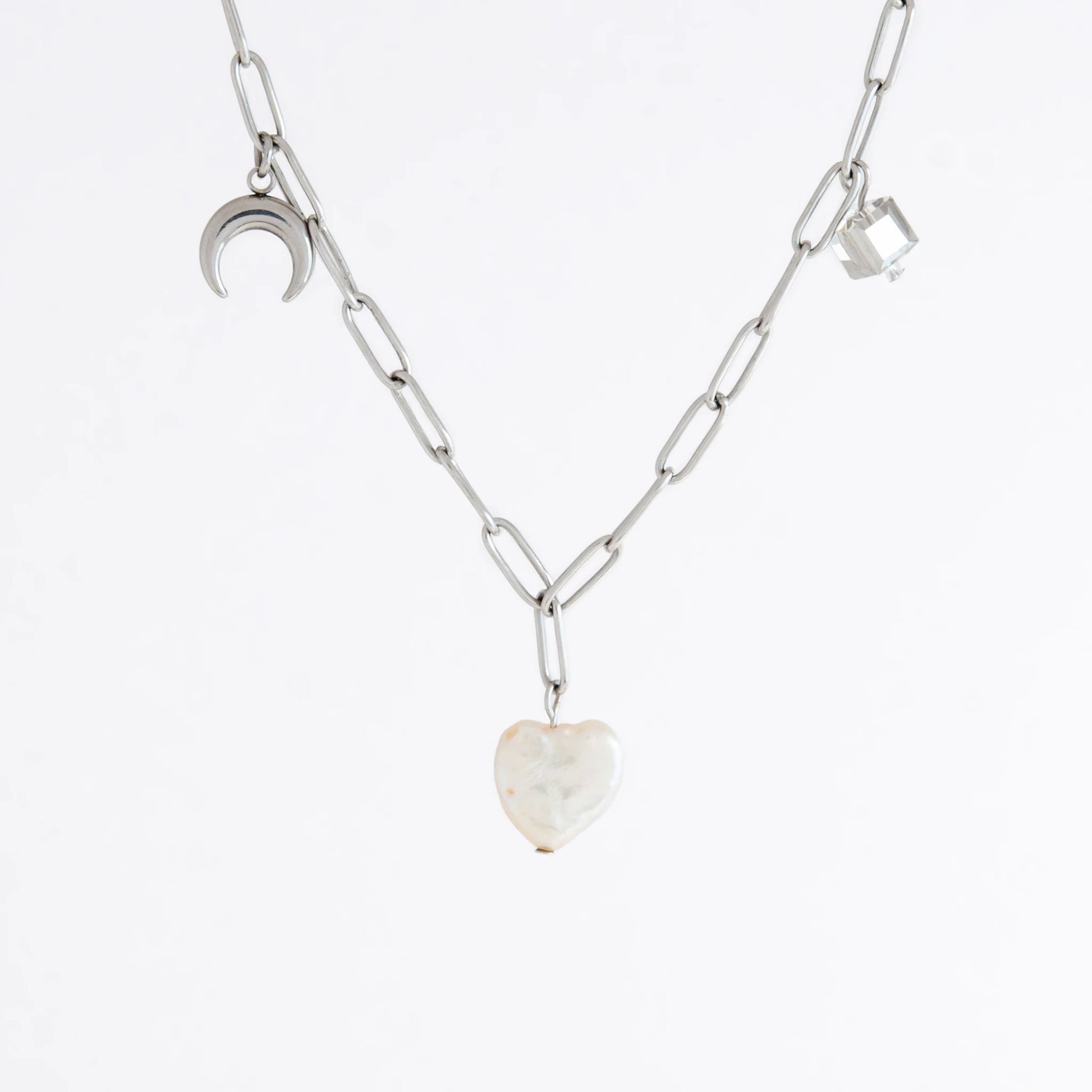 Silver chain charm necklace with pearl pendants, glass bead, and star pendants on a light gray background