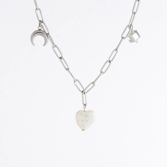 Silver chain charm necklace with pearl pendants, glass bead, and star pendants on a light gray background